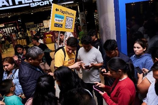 A crowd of people looking at phones around a PagoEfectivo promoter at an in-store activation.