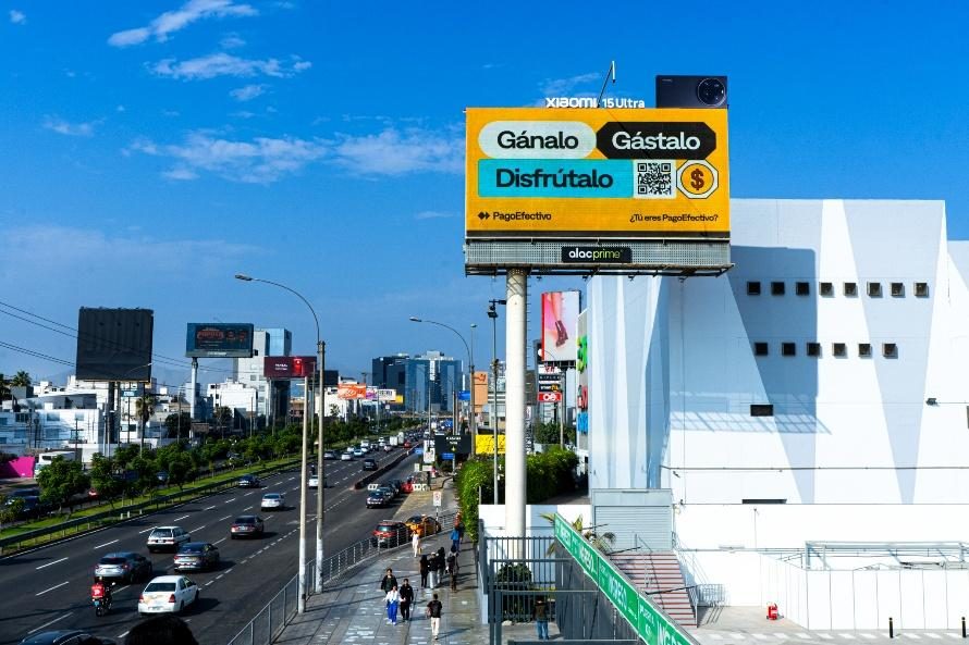 A large yellow PagoEfectivo billboard above a busy road with the headline Ganalo, Gastalo, Disfrutalo and a download QR code.