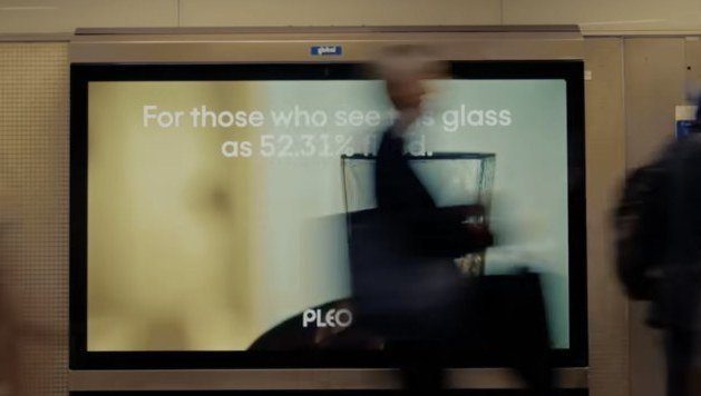 Pleo advert on an Underground platform screen with the line For those who see the glass as 52.31% full.